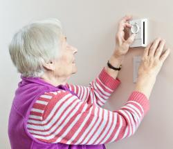 older woman checking thermostat