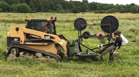 Hatch drives fiber optic plow on skid steer through bog laying cables within the bog