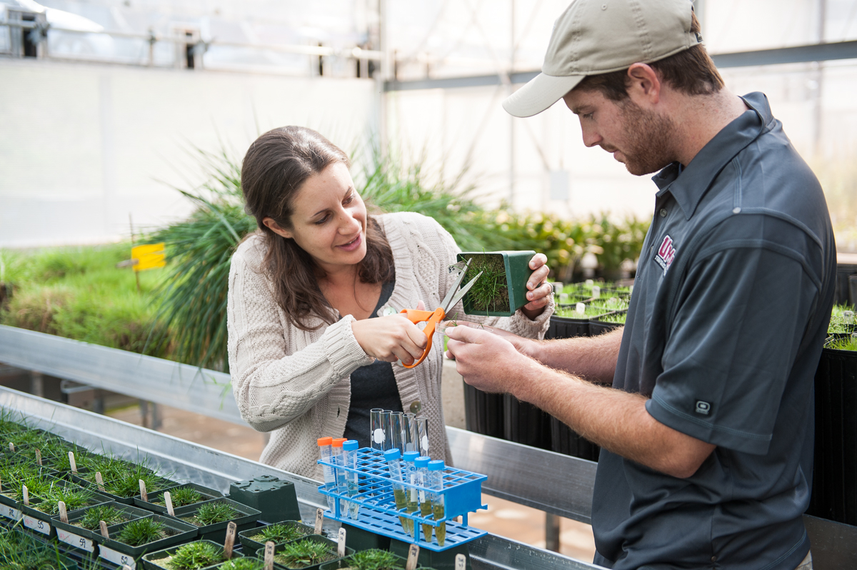 Michelle DaCosta trains student in greenhouse