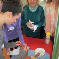 Judy Vollmer instructs students in how to properly diaper an infant