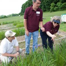 Mary Owen, turf team leader, points out characteristics of grass to Jeff Doherty and John Clark 