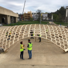 Wood dome shell raising with Design Building in background