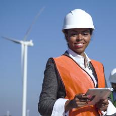 Professional woman in hardhat in front of wind turbine