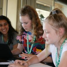 Three 4-H young women work on creating a phone app