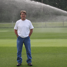 Scott Ebdon with high-arc sprayer watering turf