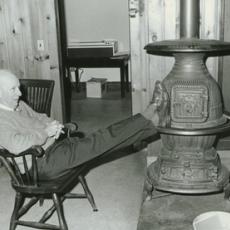 Dr. Chester Ellsworth Cross, with feet on woodstove