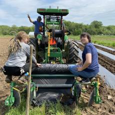 Student Matthew Bley (right) catches a ride while learning about healthy soil
