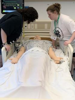Youth assessing the condition of a sim at the nursing simulation lab. 