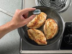 checking temperature of chicken on stove top