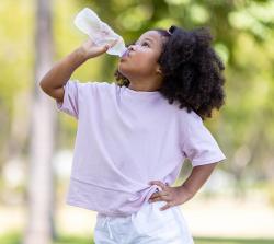 young girl drinking water from a plastic bottle