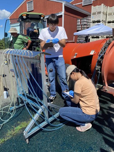 Students Matthew Bley and Lauren Ho take notes on pesticide machine calibration during their REEU internship. 