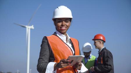 Professional woman in hardhat in front of wind turbine